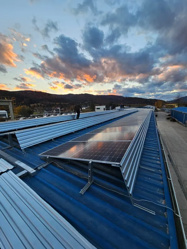 Panouri fotovoltaice pe acoperișul unei hale, la apus